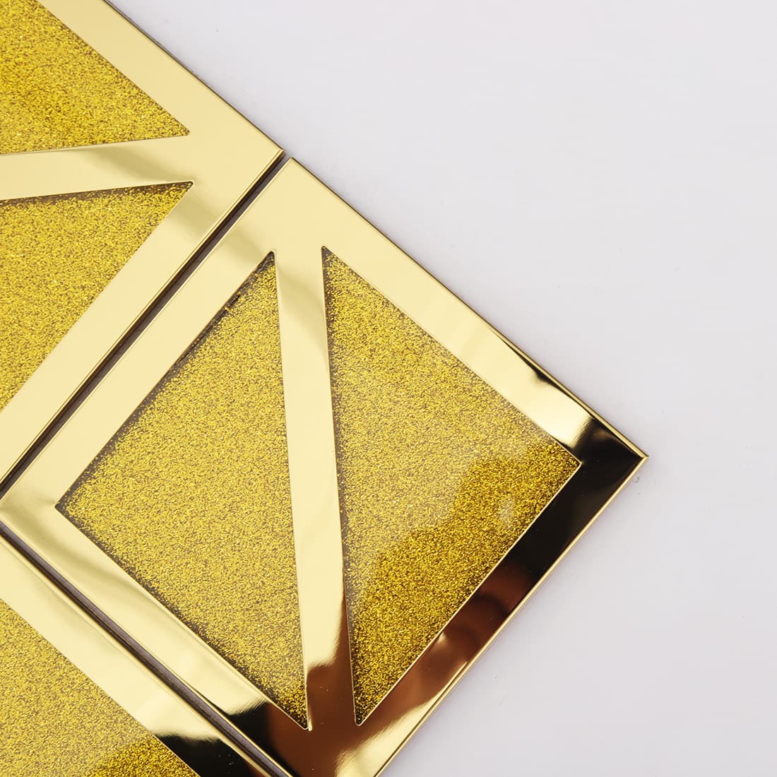 Close-up of gold square mosaic tile with glitter insert and framed diagonal accent
