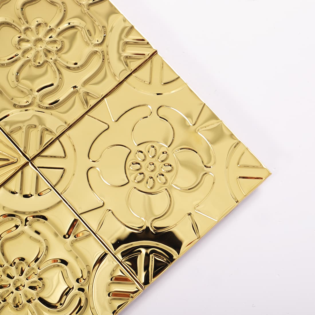 Corner close up of gold stainless steel embossed floral mosaic tiles