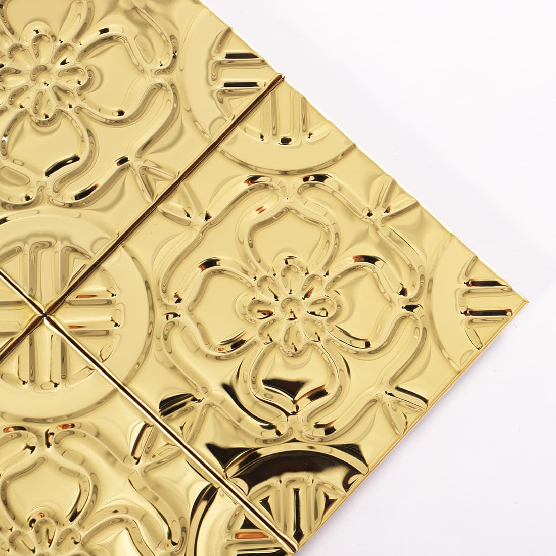 Corner detail of gold stainless steel embossed floral square tiles