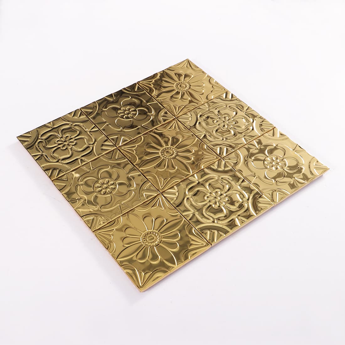Angled view of gold stainless steel mixed floral embossed mosaic sheet