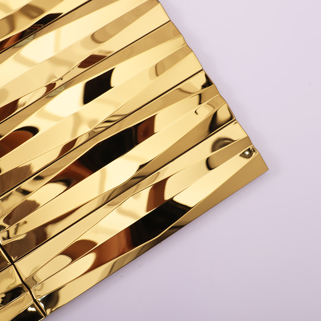 Close-up of gold wavy linear stainless steel mosaic tile corner