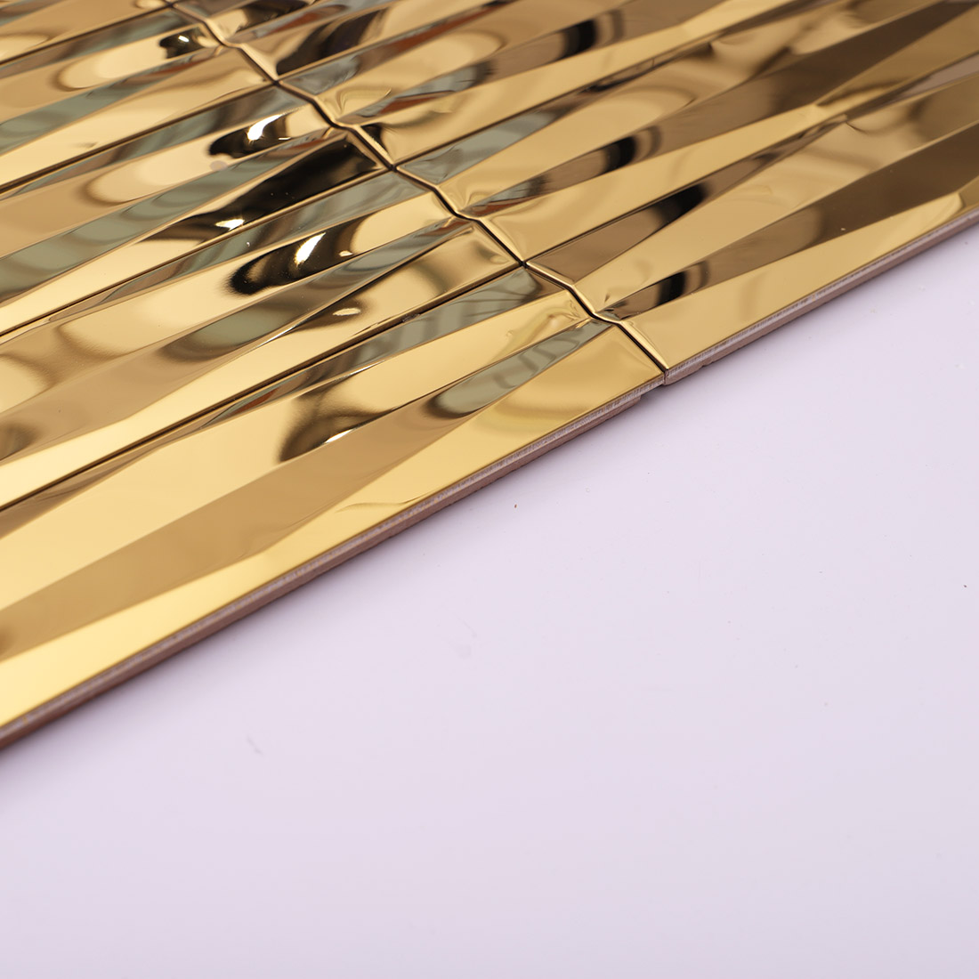 Edge detail of gold wavy linear stainless steel mosaic tile sheet