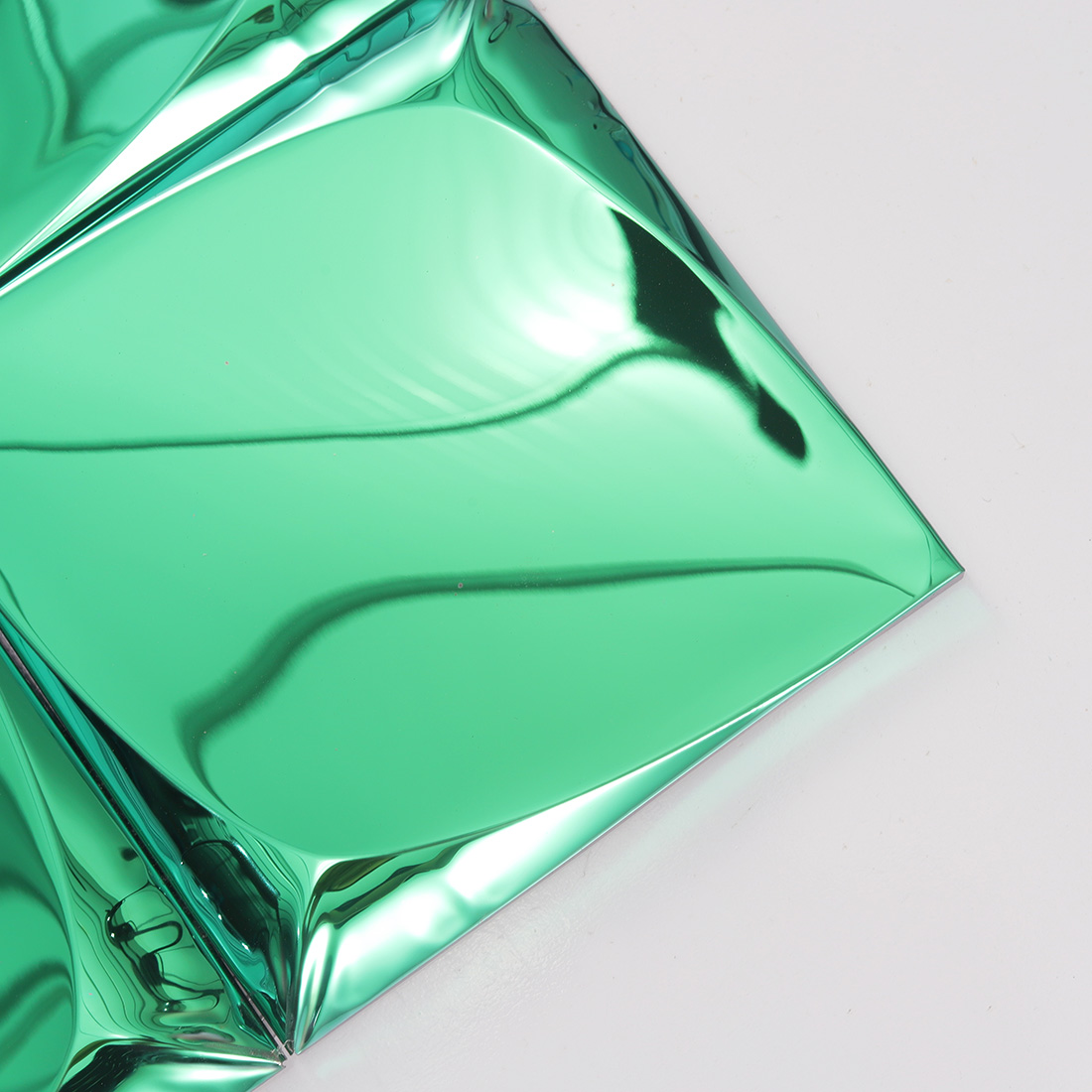 Closeup of green 3D metal tile corner with glossy raised pyramid surface