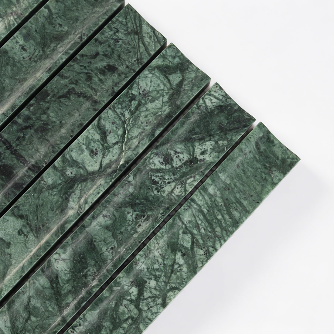 Close-up of elegant curved flutes on emerald green marble tile.