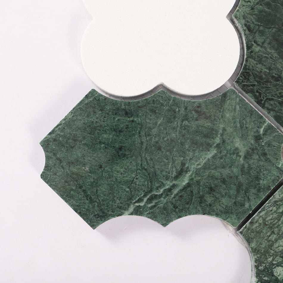 Close up of green marble waterjet mosaic tile edge and white quatrefoil curve