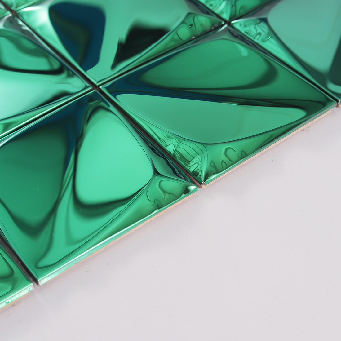 Edge view of green raised square metal tile with glossy geometric surface