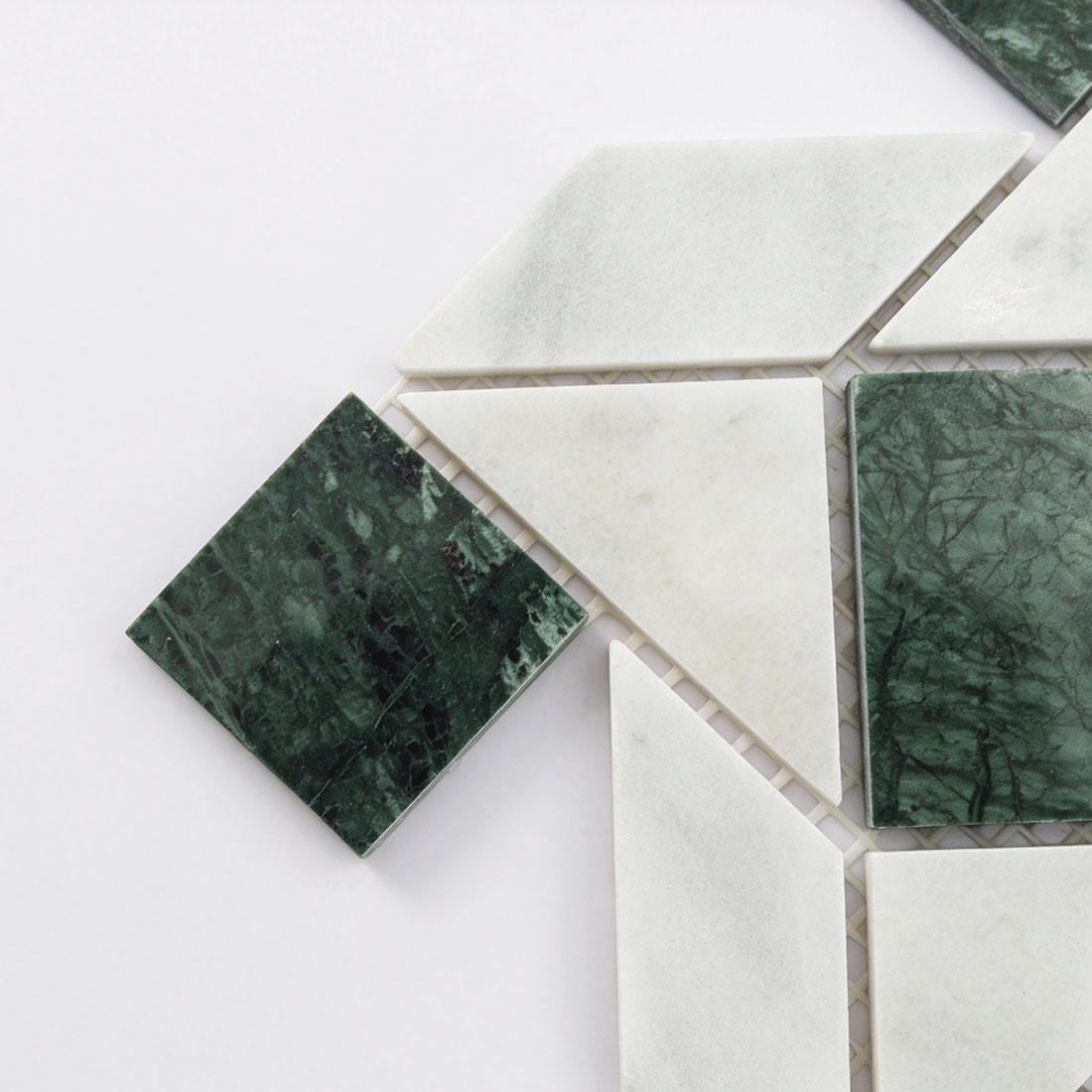 Corner detail of green and white geometric pinwheel marble mosaic tile sheet.