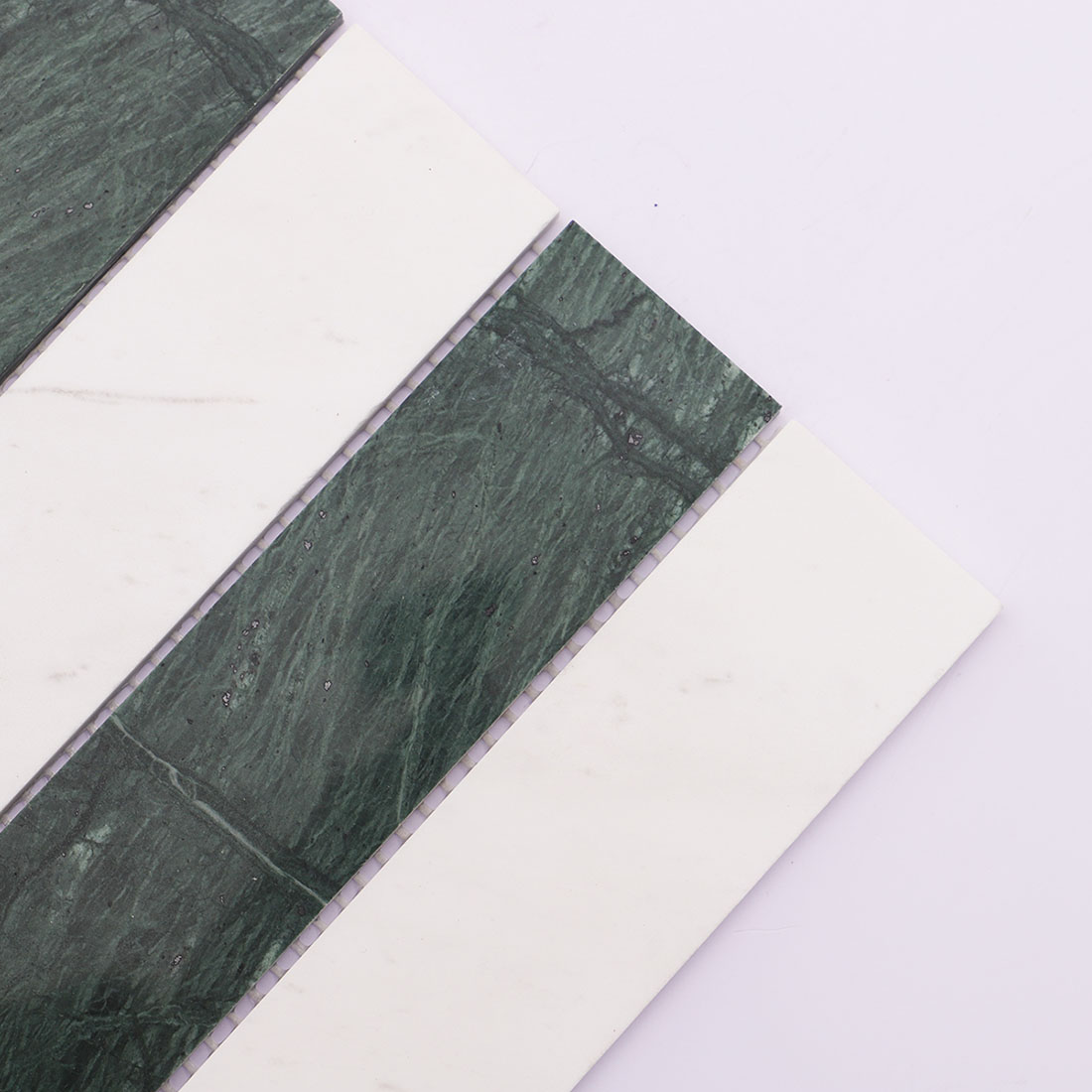 Angled view of green and white vertical marble mosaic with long strip pattern.