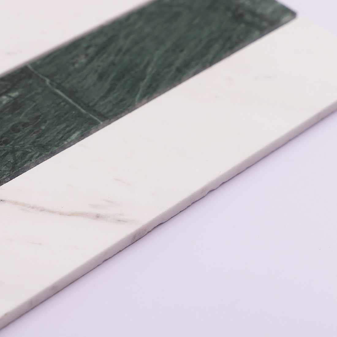Side view of green and white marble strip mosaic tile showing thickness.
