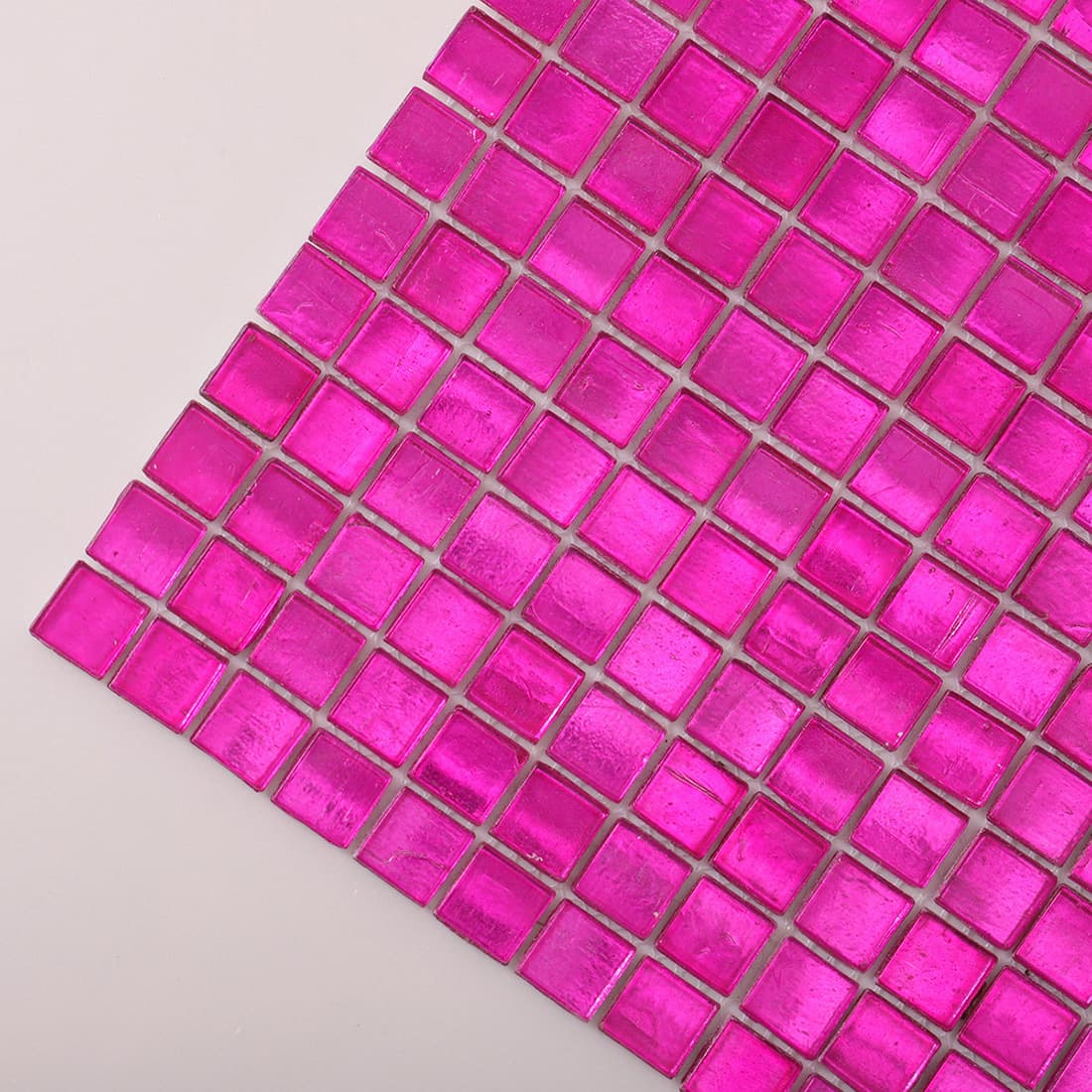 Angled close-up of hot pink foil-backed square glass mosaic