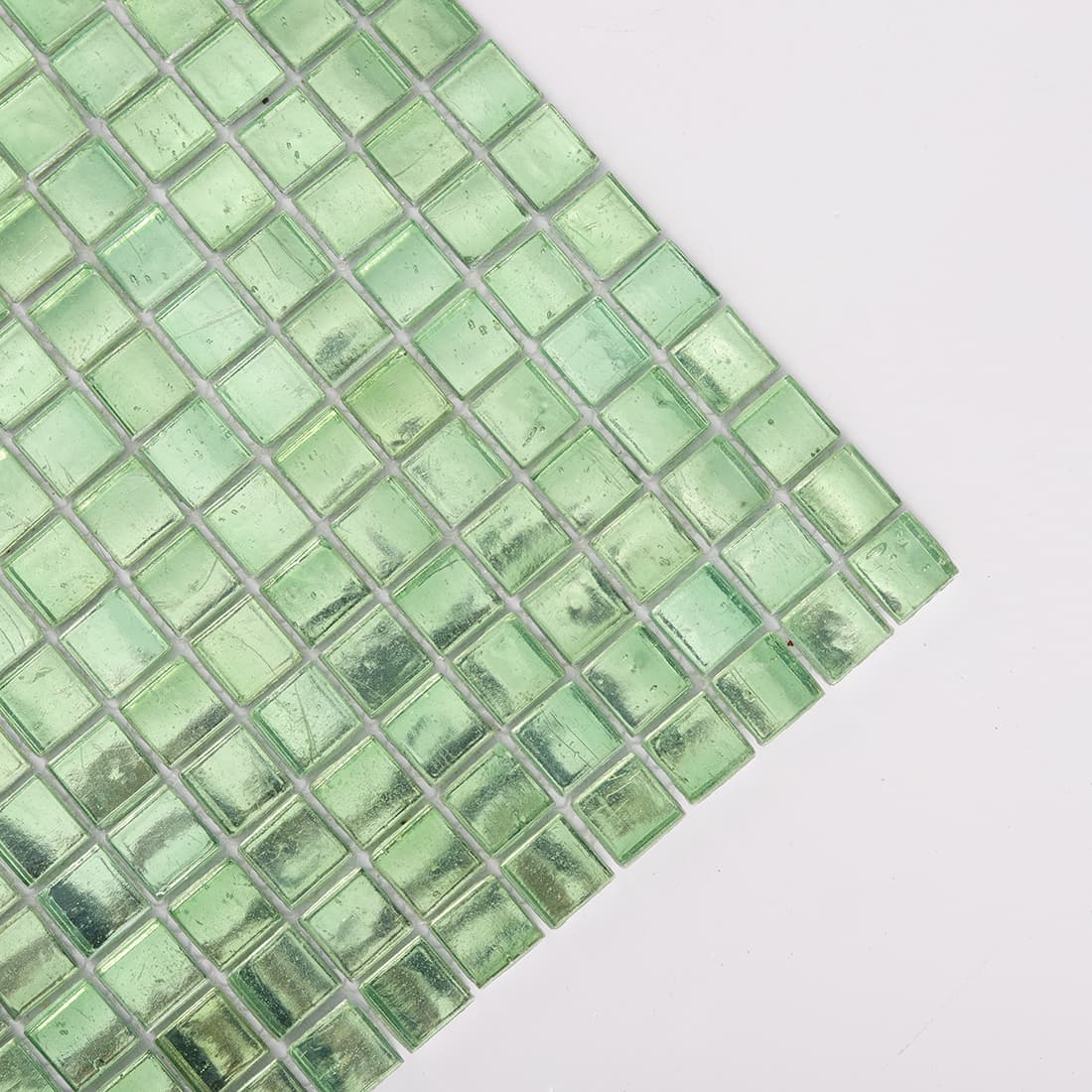 Corner close up of light green square glass mosaic tile sheet
