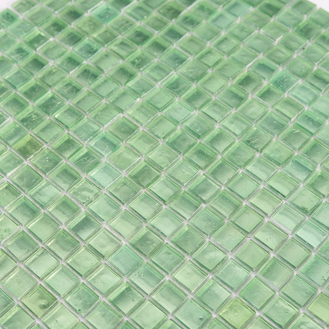 Surface detail of light green square glass mosaic tile in diagonal view