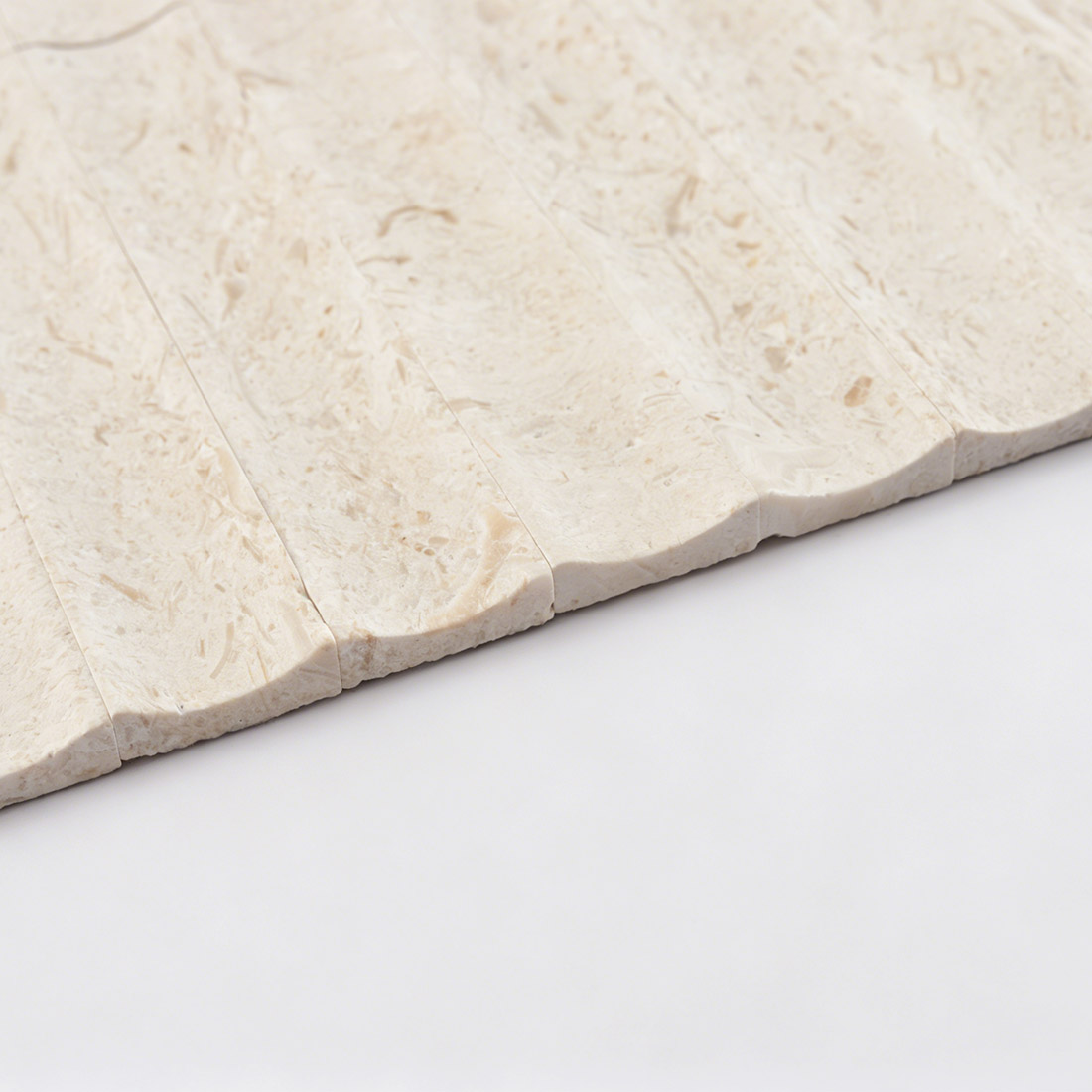 Edge profile showing the seamless wave contour of beige limestone tile.