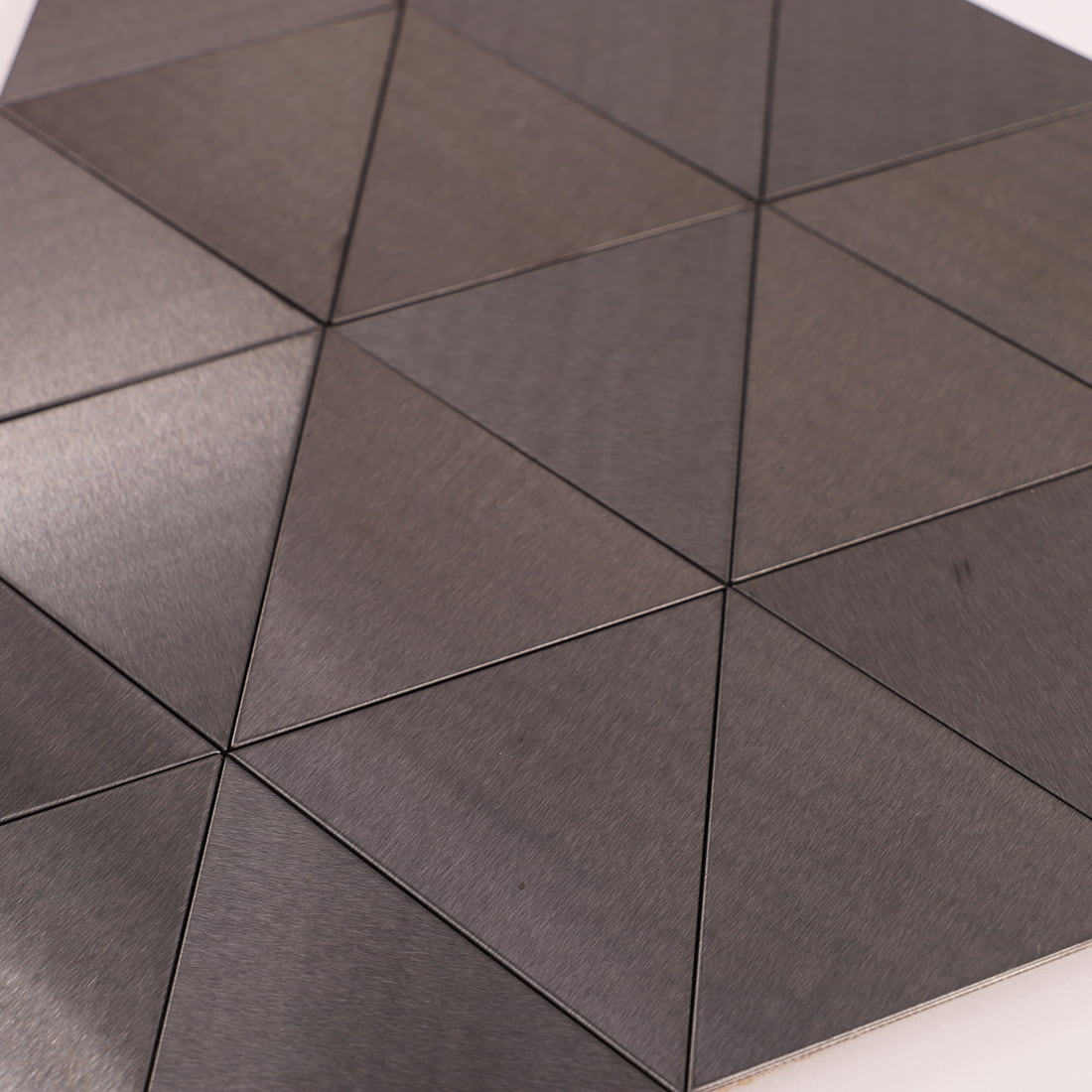 Low angle view of gray metallic triangular tiles reflecting soft light.