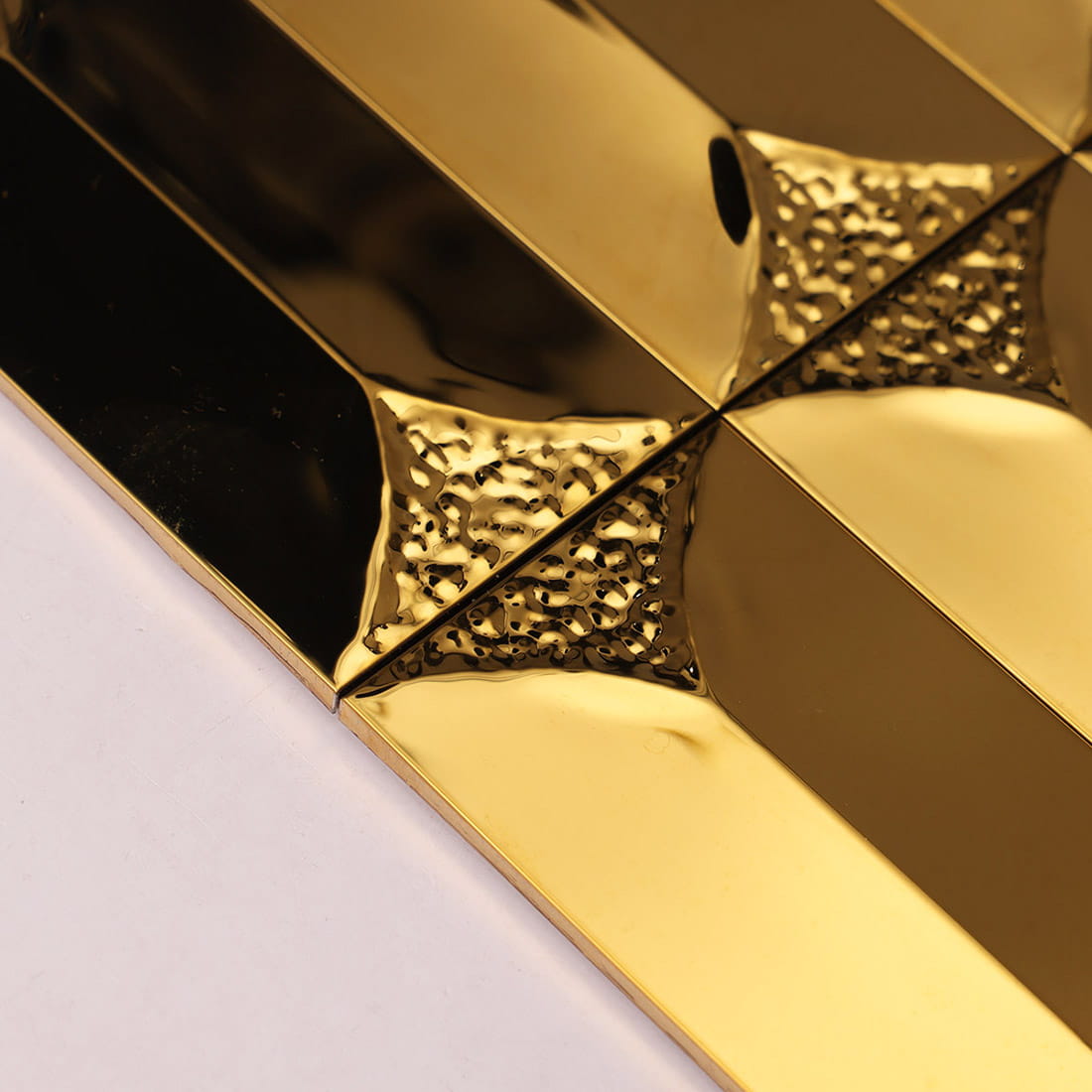 Extreme close-up of the hammered texture on gold metal tiles.