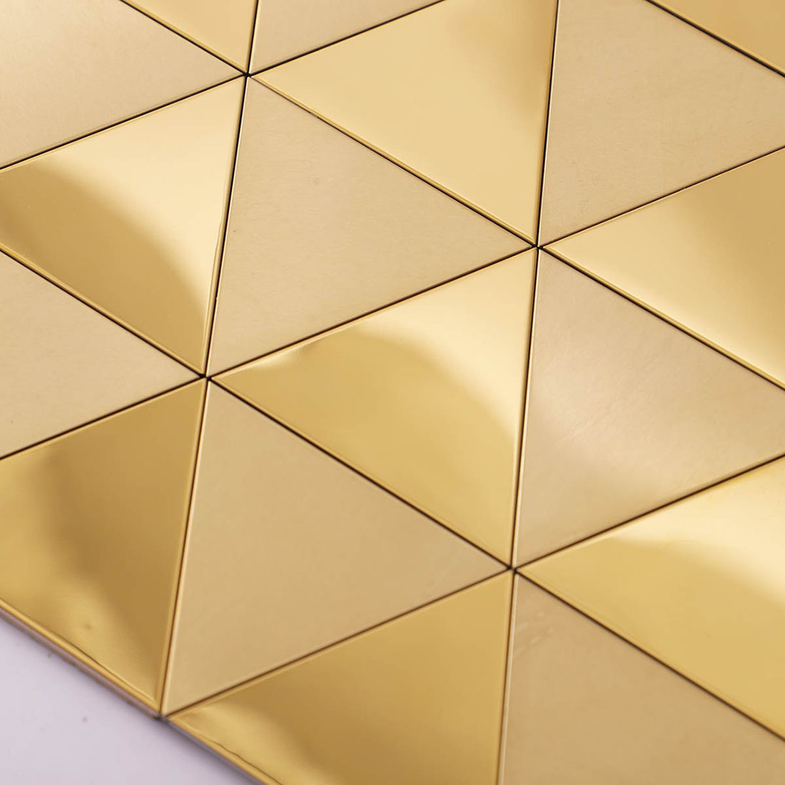Detailed macro view of tight joints on reflective gold triangular metal tiles.