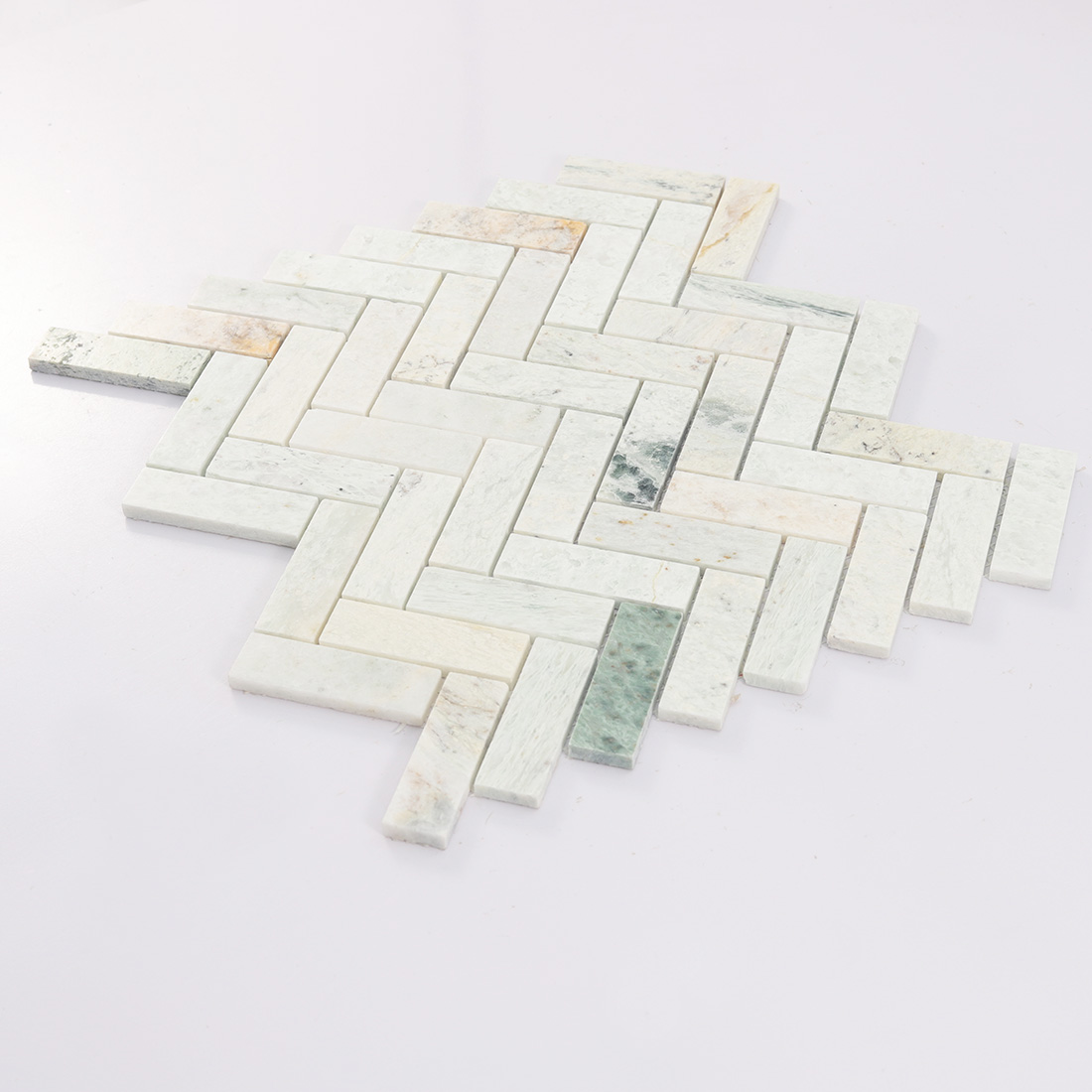 Angled view of white and green marble herringbone mosaic.