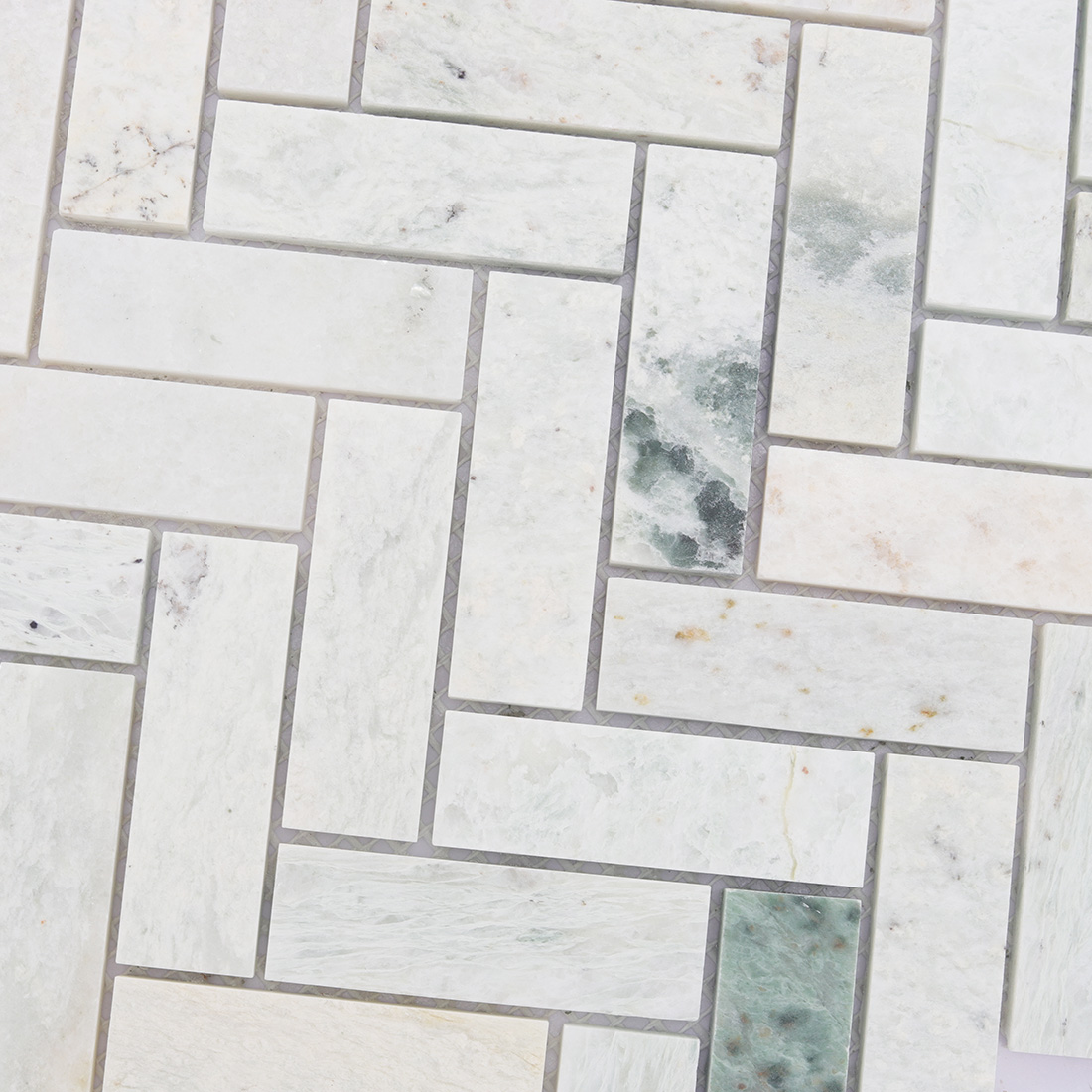 Detailed texture of white and green marble herringbone mosaic.