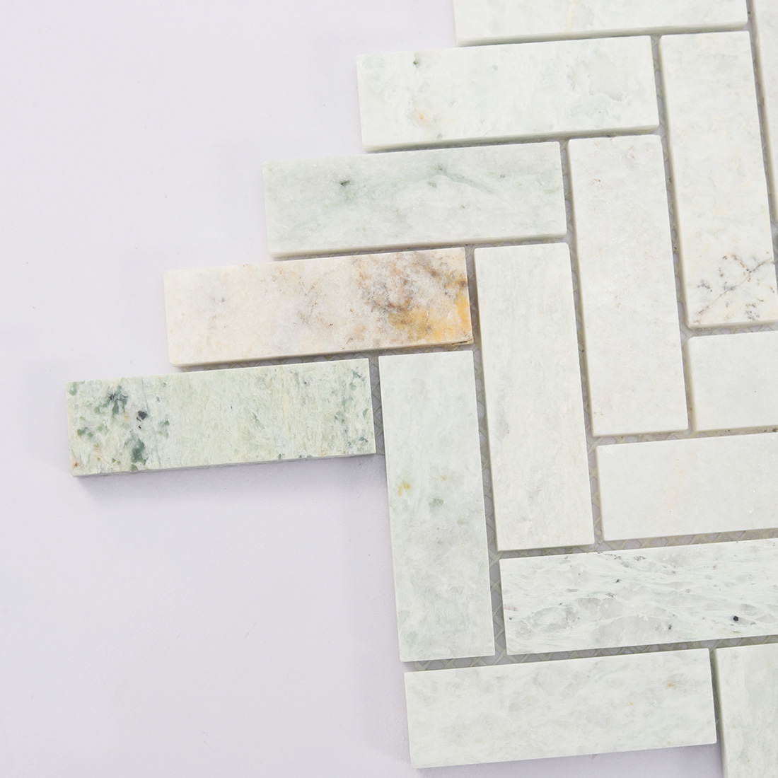 Close-up of the left edge of marble herringbone mosaic tile.