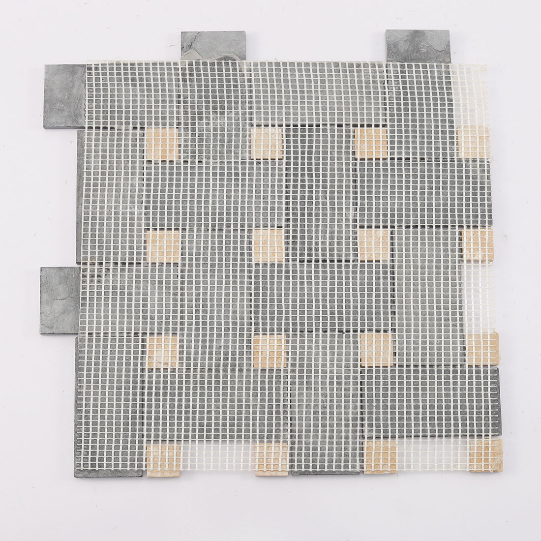 Back view of black and yellow marble basketweave tile with fiber mesh backing