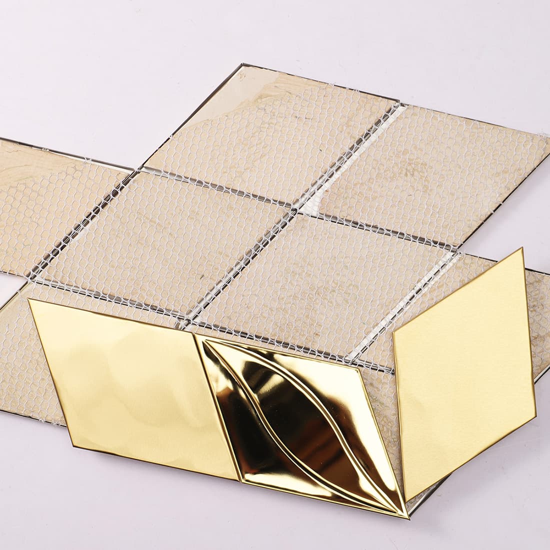 Back view of gold metal diamond tiles showing the adhesive mesh backing.