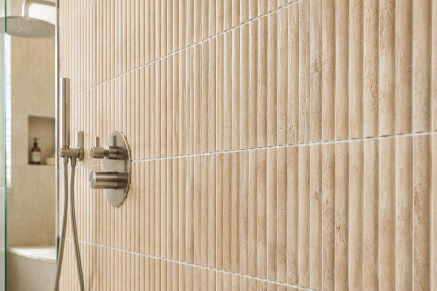 Beige fluted shower wall tiles in a modern walk-in shower with glass enclosure
