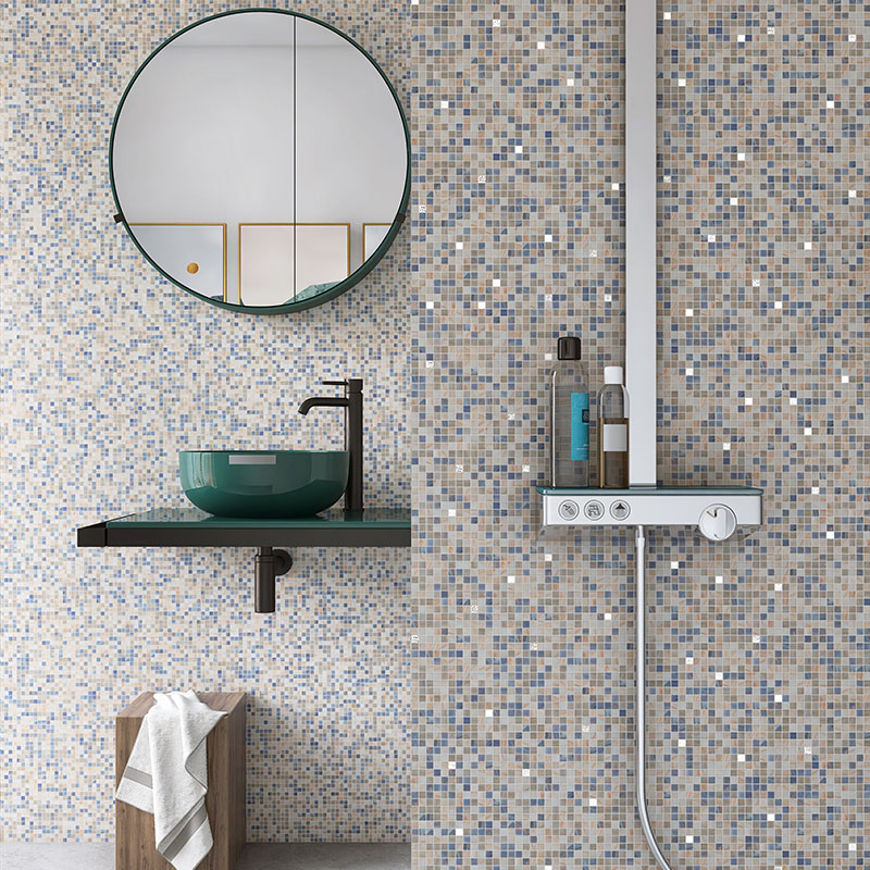 Complete bathroom view with a green vessel sink, round mirror, and a multi-toned mosaic tiled wall.
