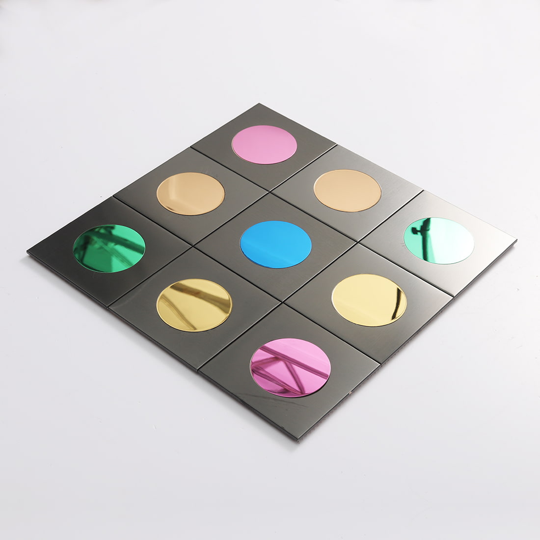 Angled view of black square metal mosaic with colorful circular mirror inserts
