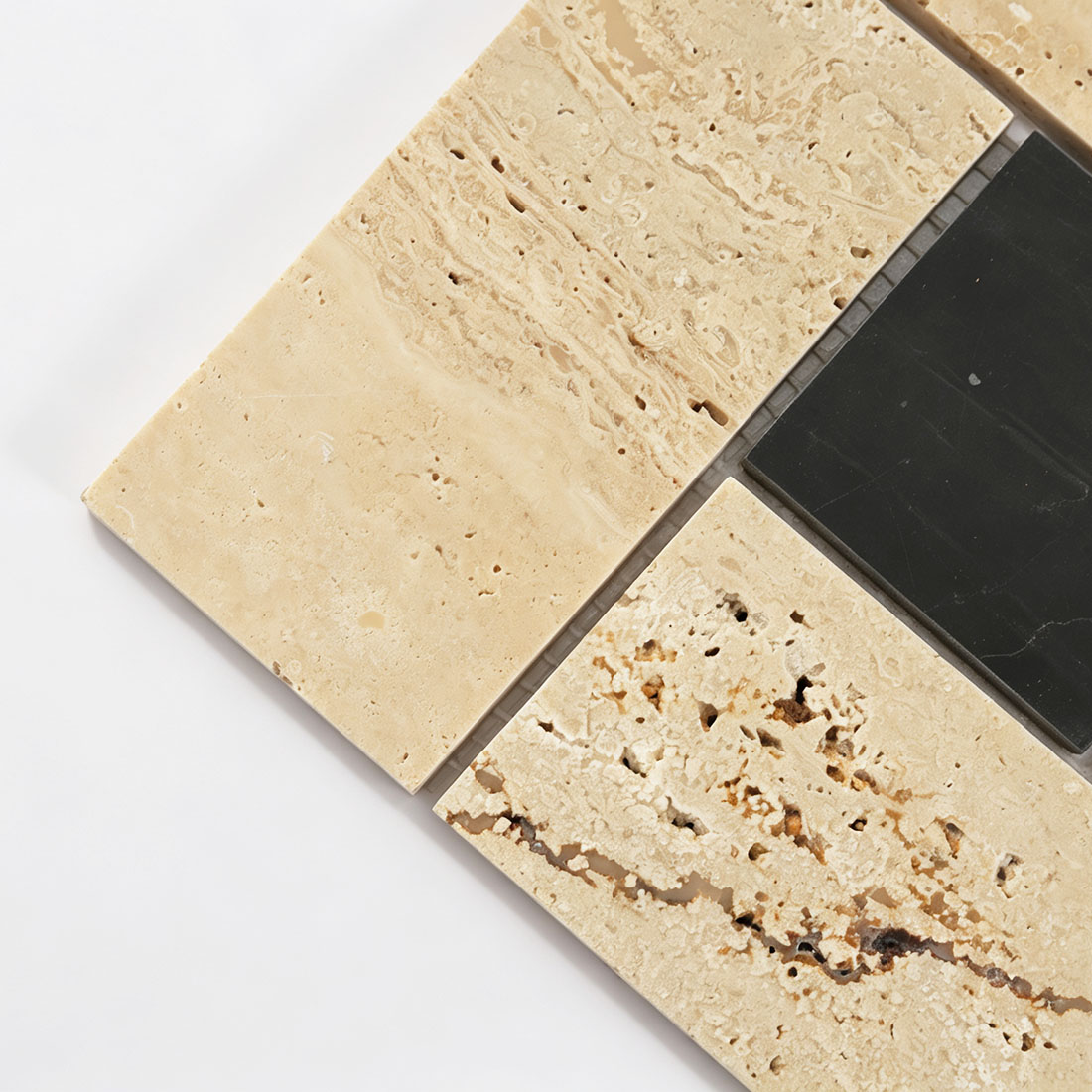 Detailed view of porous travertine and smooth black stone mosaic tile pieces