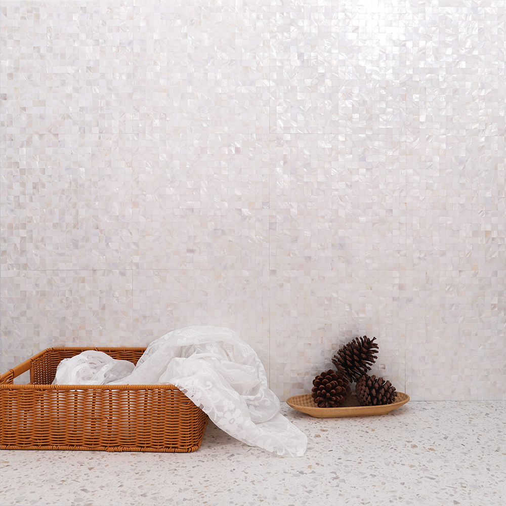 White shell mosaic tile wall with basket, cloth and pine cones.