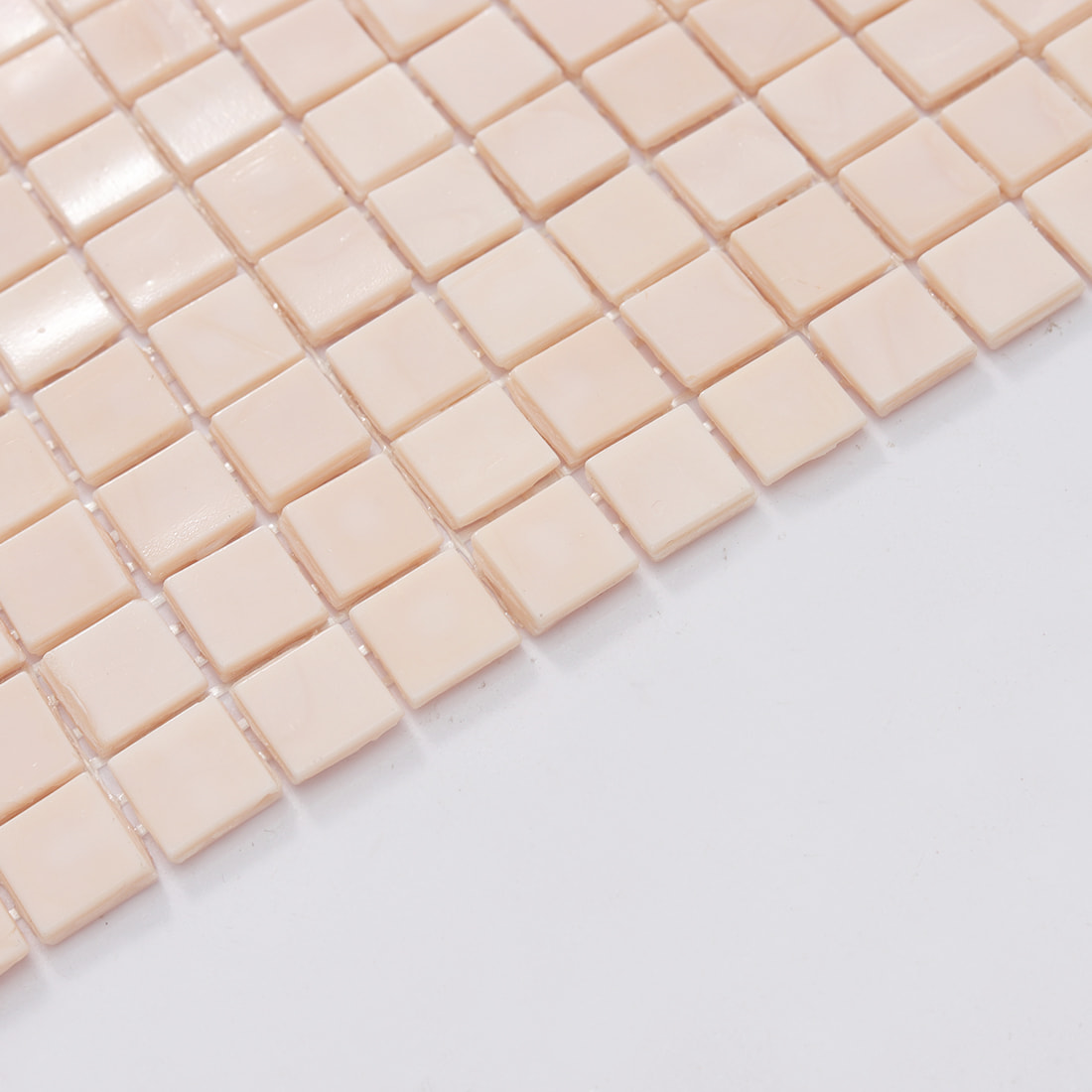 Edge close-up of pale blush square glass mosaic tile