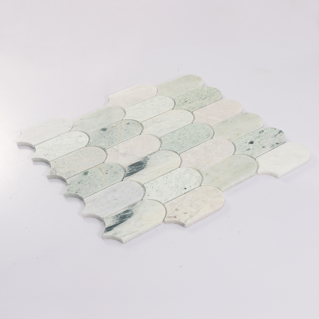 Angled detail of pale green long scallop marble mosaic tile with curved edges