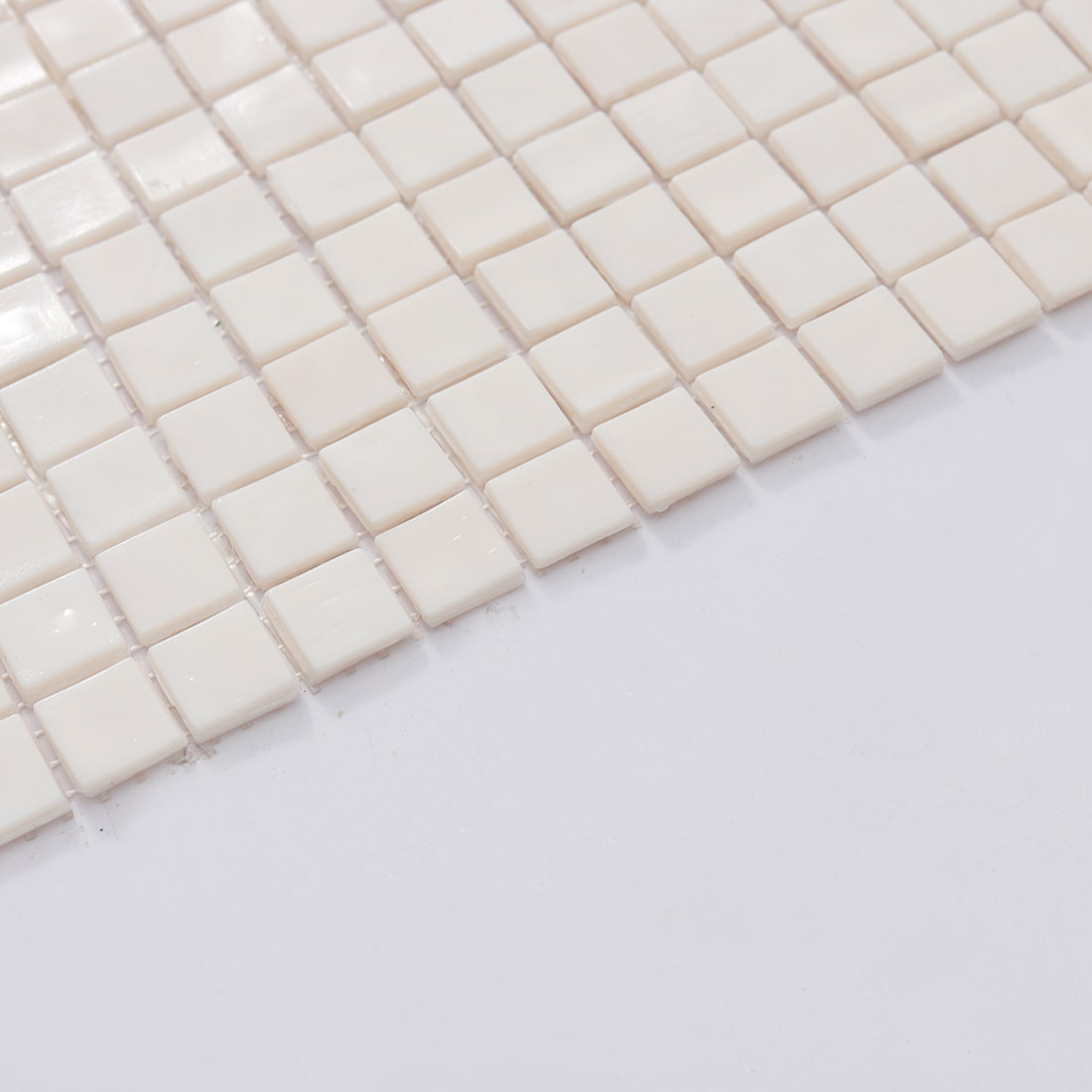 Edge close up of pale pink square glass mosaic tile sheet