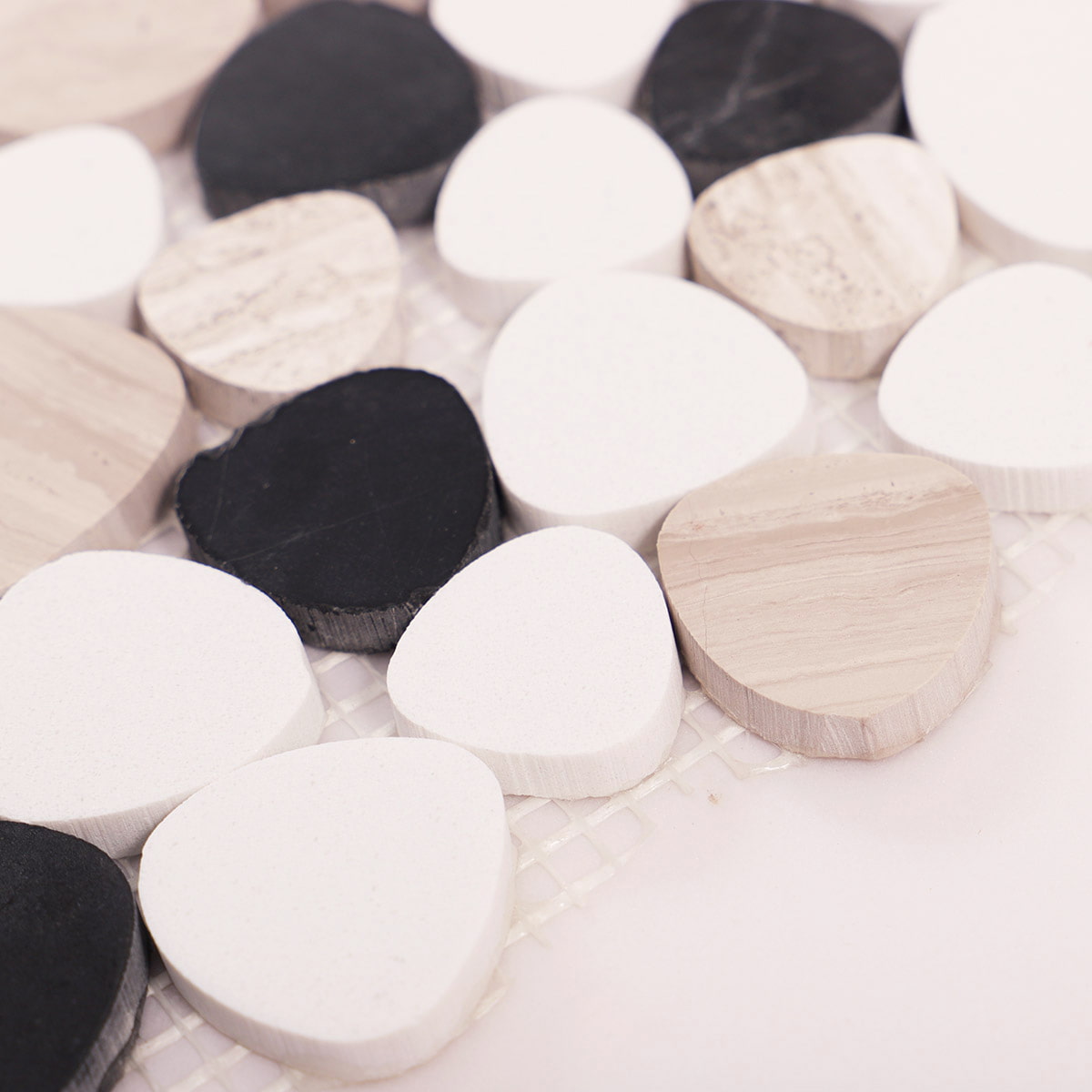 Macro detail of white black and beige pebble mosaic tiles on mesh backing