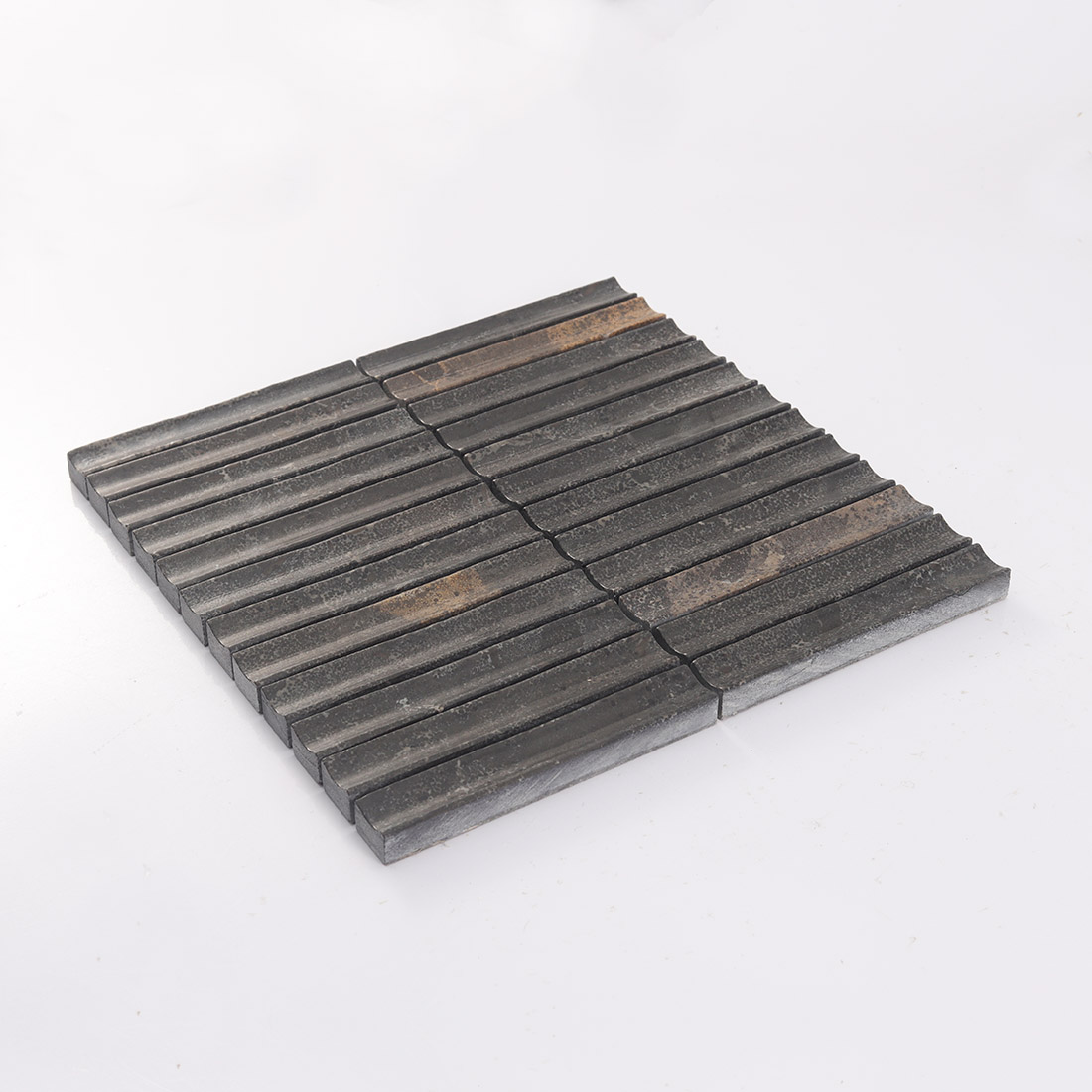 Perspective view of a 3D fluted dark brown stone mosaic wall tile on white surface.