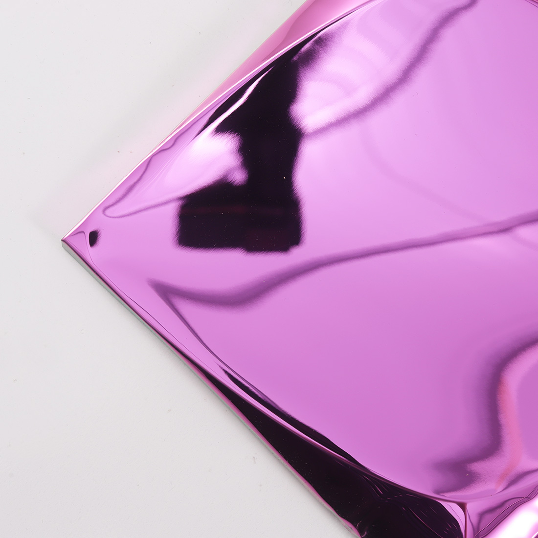 Closeup of pink 3D metal tile corner with reflective folded surface