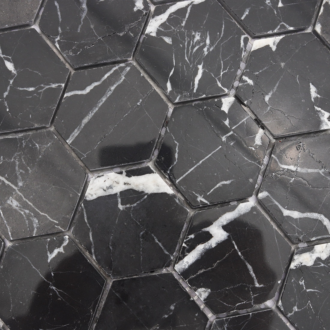 Polished black hexagon marble mosaic showing bold white veining texture