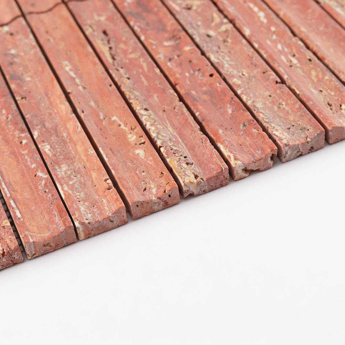 Edge close-up of red travertine linear mosaic.