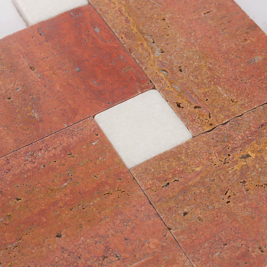 High angle detail of white square accent on red travertine mosaic