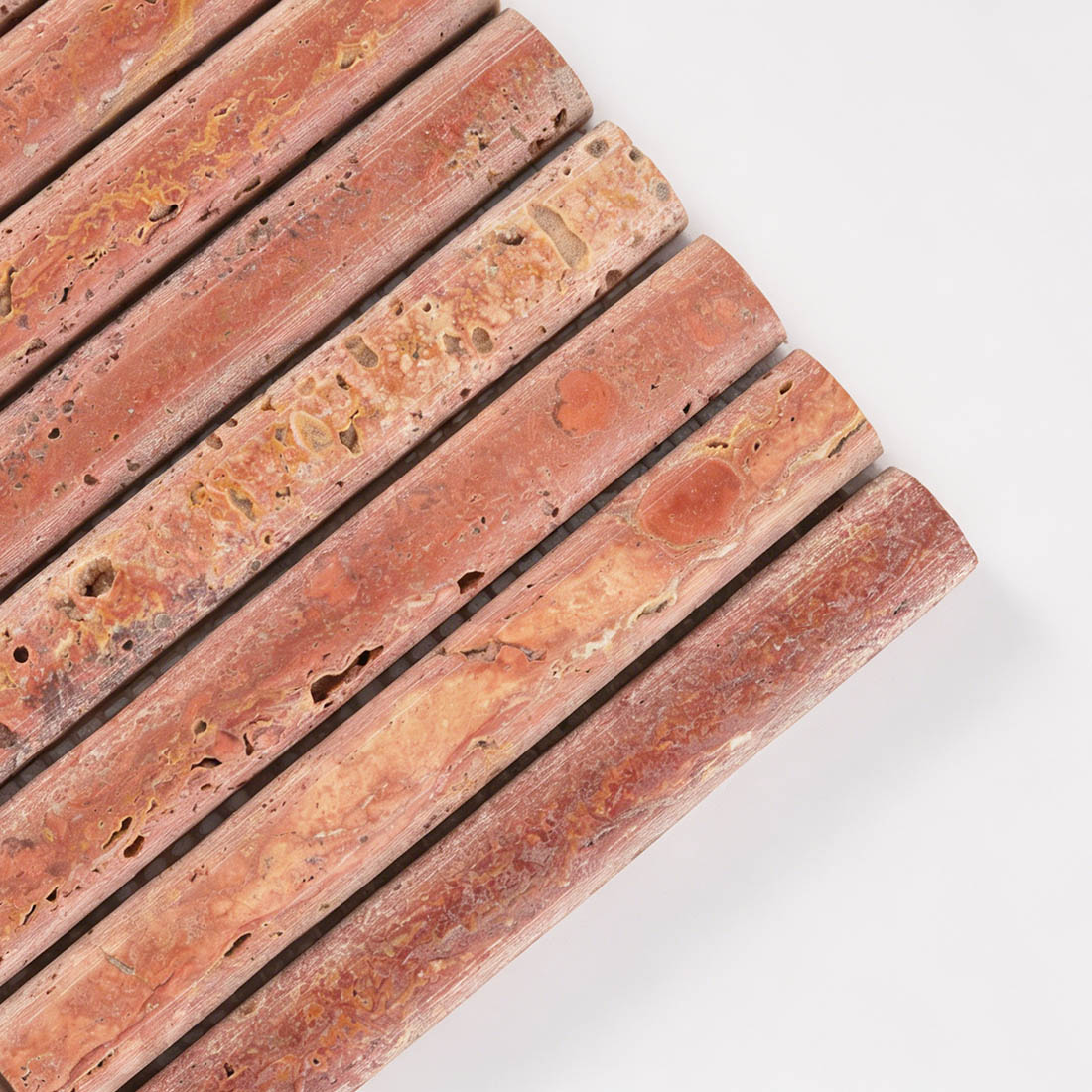 Close-up corner detail showing the rod texture of red travertine tile.