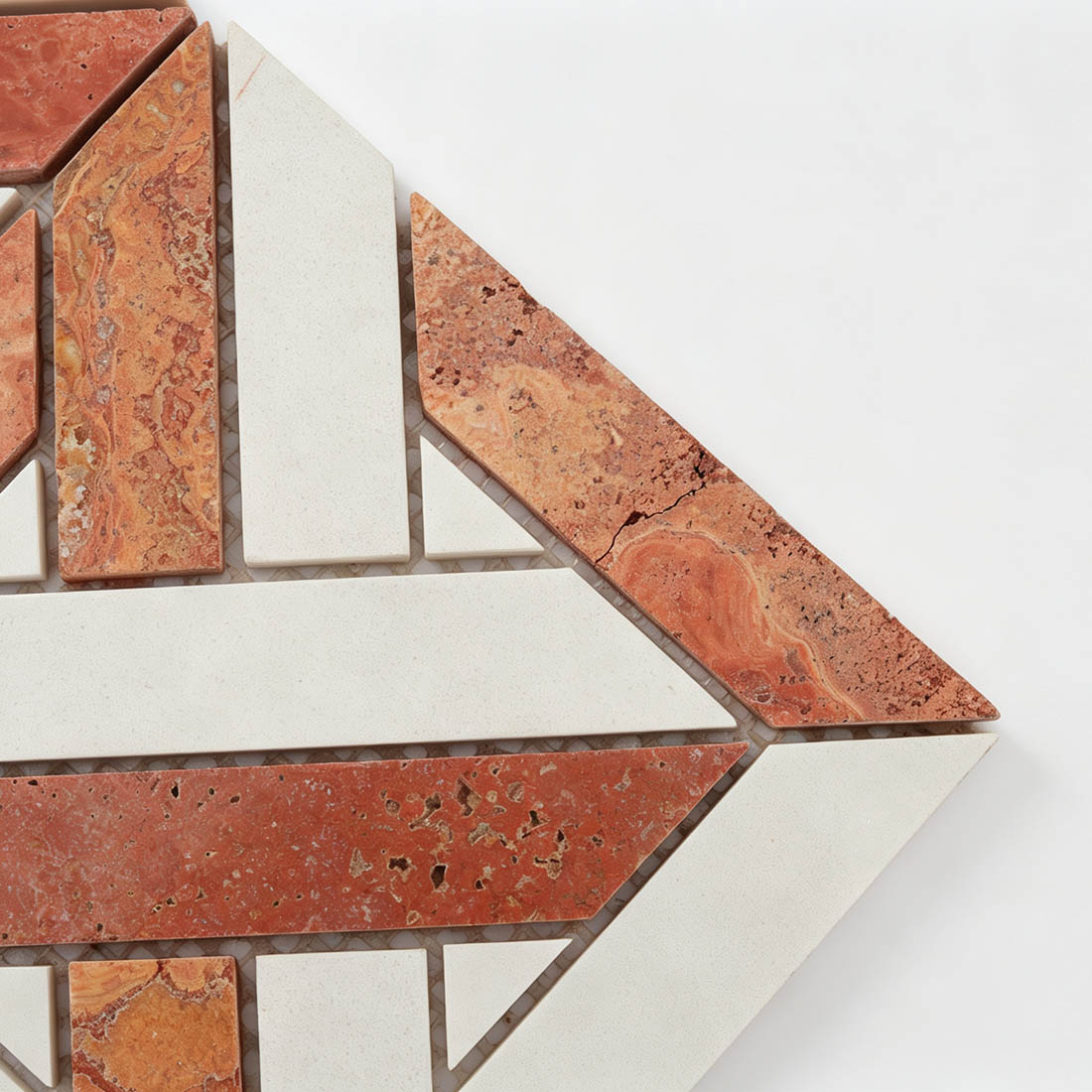 Close-up of red white interlocking geometric marble mosaic with angled stone pieces