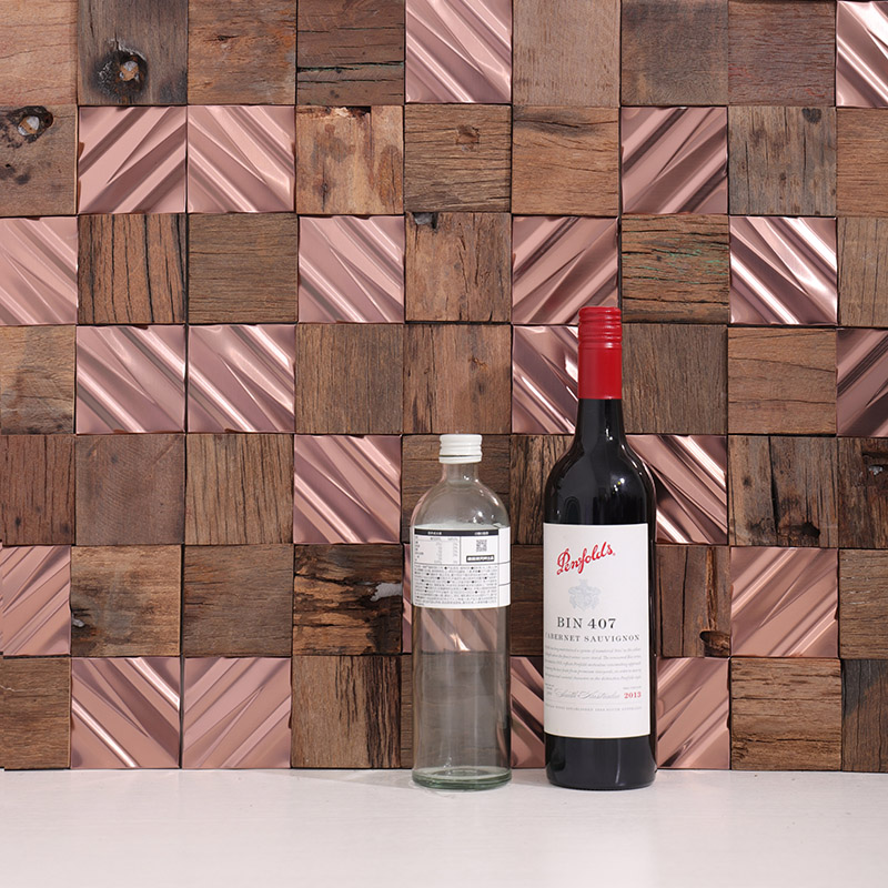 Retro wood and rose gold metal mosaic backsplash with wine and water bottles.