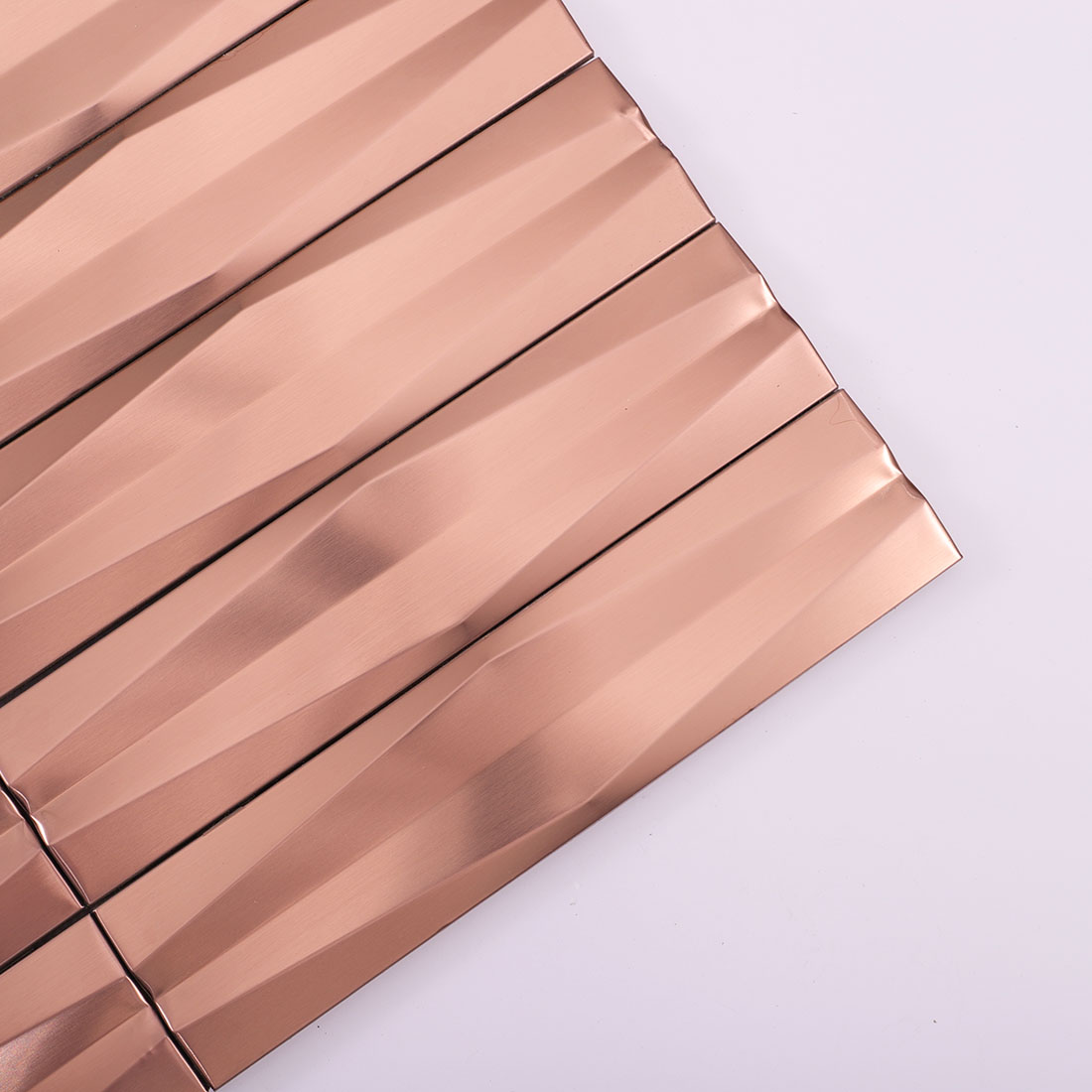 Close-up of rose gold 3D linear stainless steel mosaic tile corner