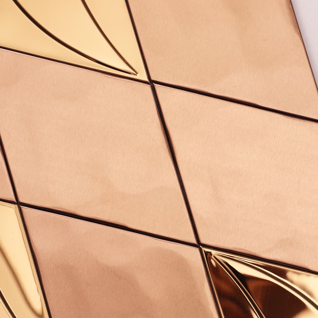 Close up of rose gold brushed metal diamond mosaic wall tiles.