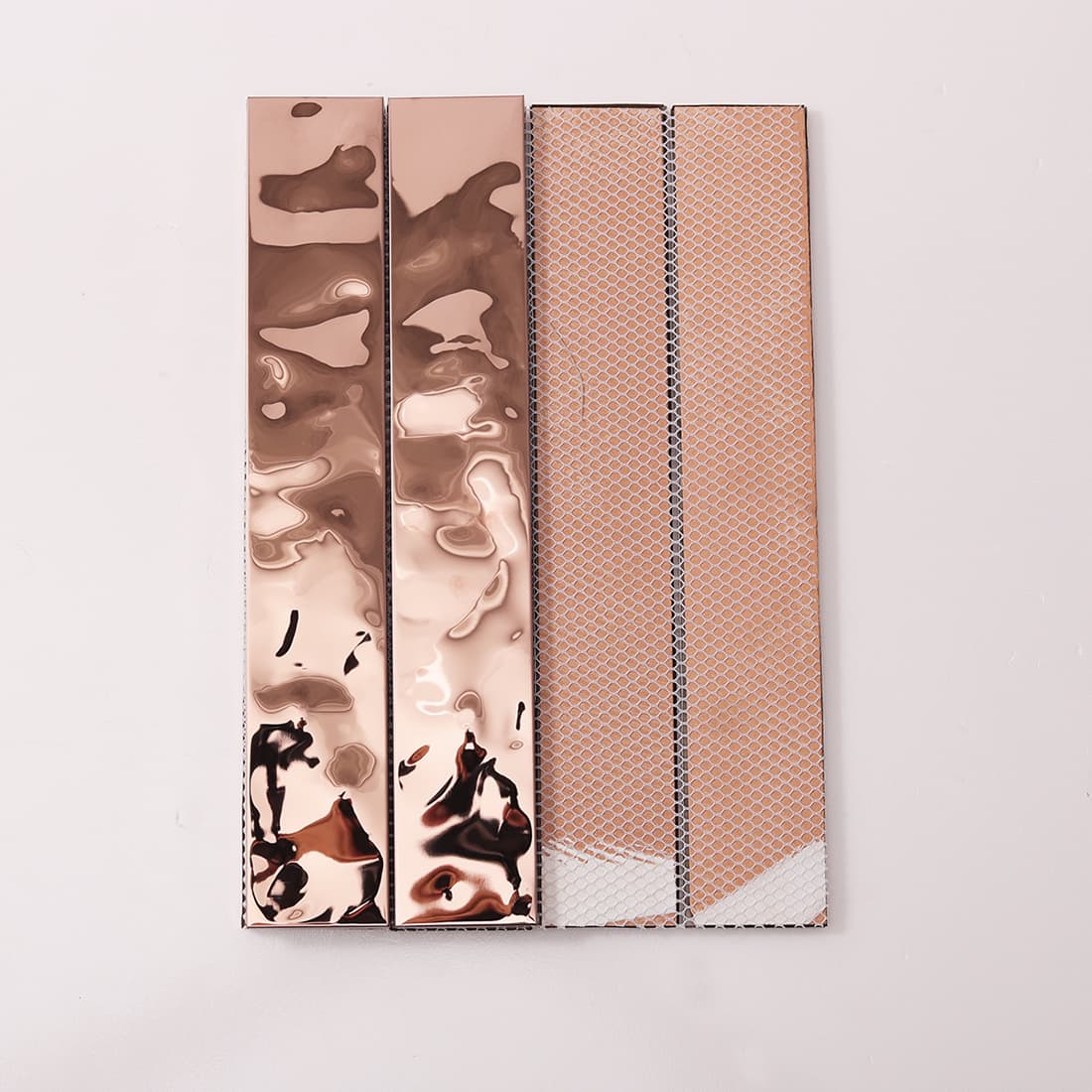 Front and back of rose gold linear tiles showing the mesh installation backing.