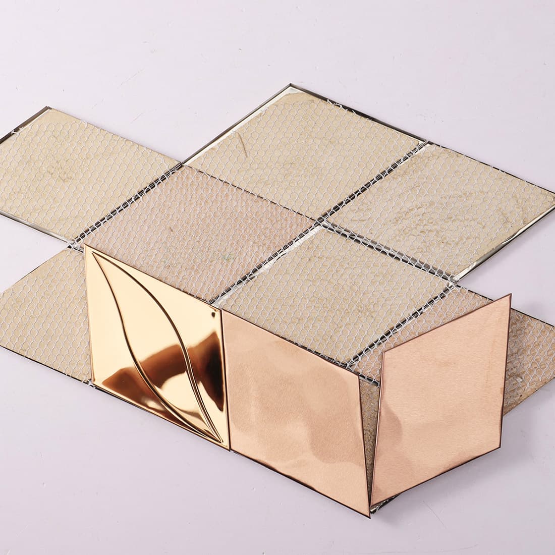 Back view of rose gold diamond metal tiles with fiber mesh backing.