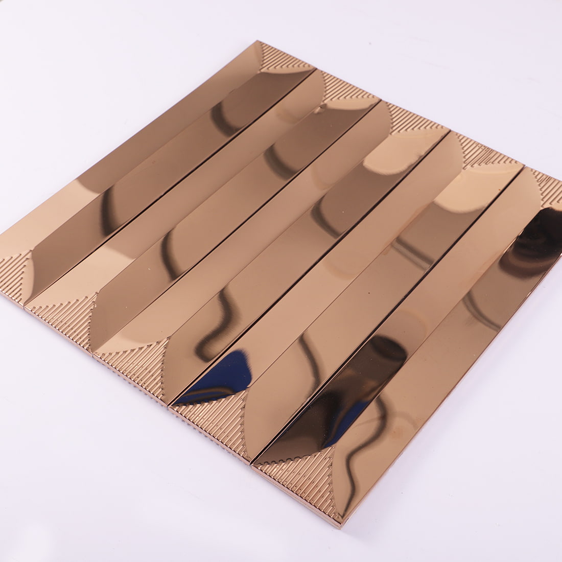 Angled view of rose gold mirror long strip metal mosaic tile sheet