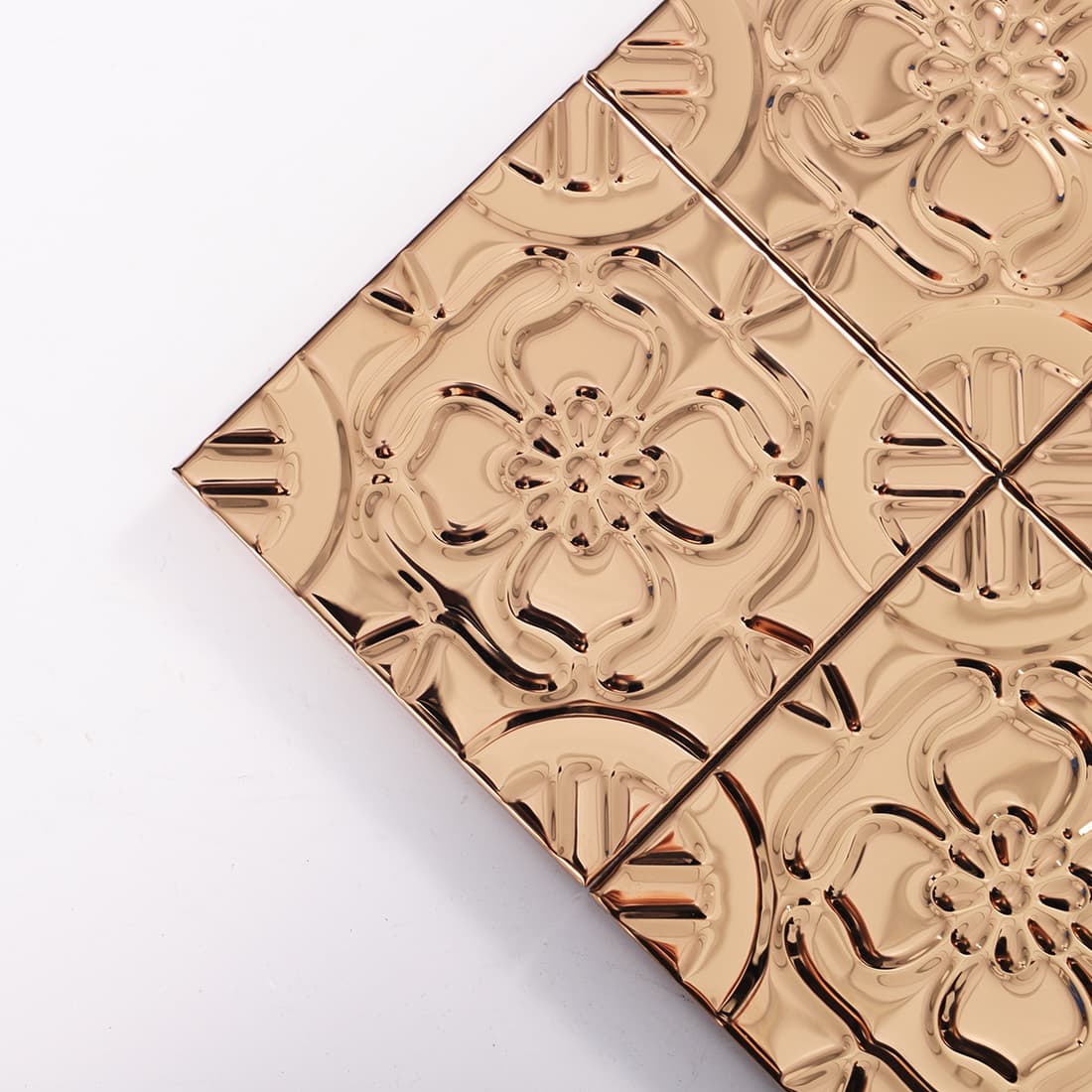 Corner detail of rose gold stainless steel embossed floral square tiles