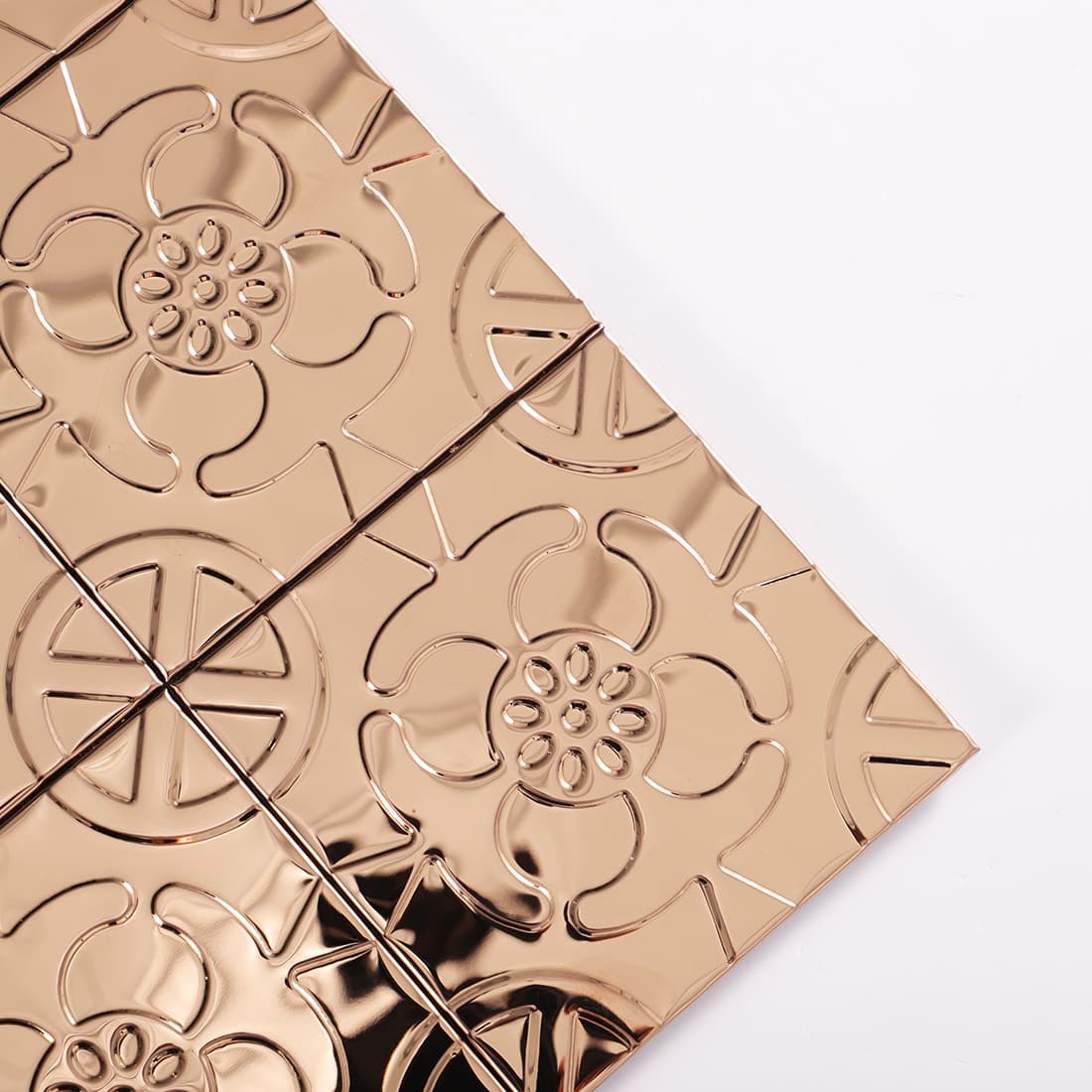 Corner detail of rose gold stainless steel floral embossed square tiles