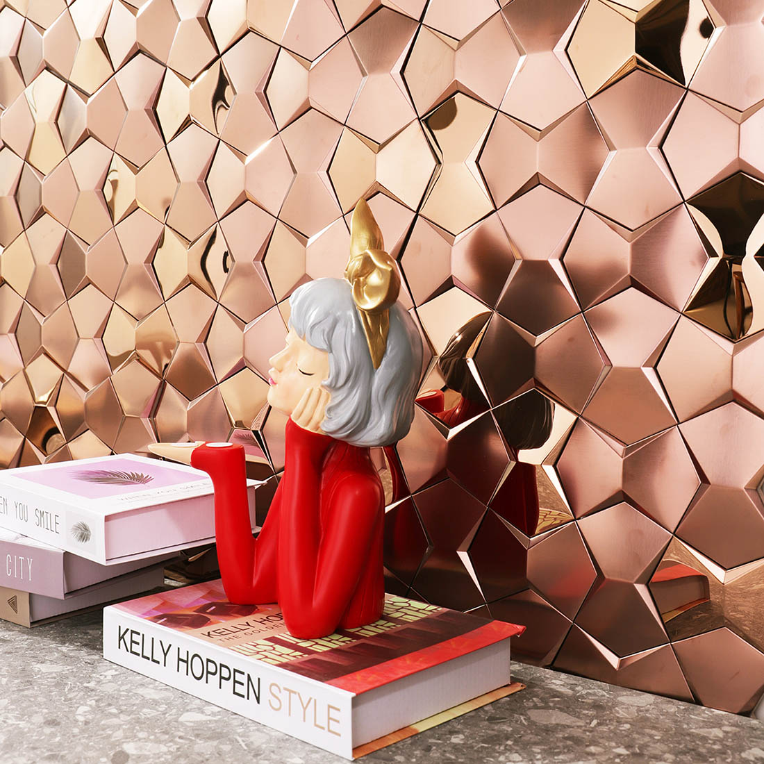 Rose gold star metal mosaic feature wall behind decorative figure and books